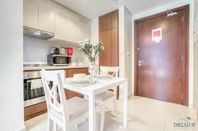 a white kitchen with a white table and chairs at Contemporary 1BR at Vera Tower Business Bay by Deluxe Holiday Homes in Dubai