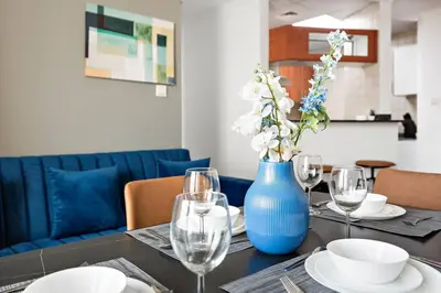 a table with a blue vase and plates and glasses at StoneTree - Stylish 1BR near Marina Walk in Dubai