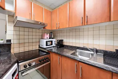 a kitchen with wooden cabinets and a sink at StoneTree - Stylish 1BR near Marina Walk in Dubai