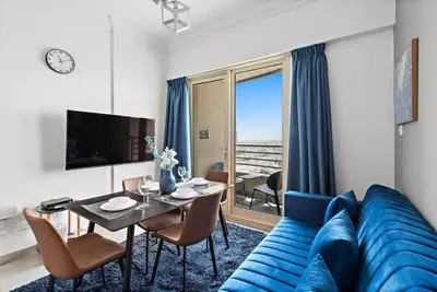 a living room with a blue couch and a table at StoneTree - Stylish 1BR near Marina Walk in Dubai