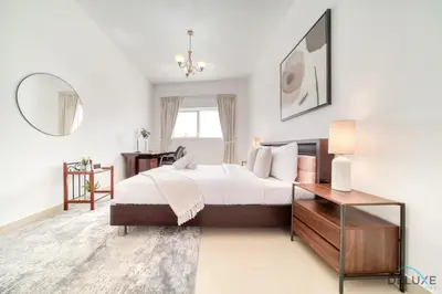 a bedroom with a bed and a table and a mirror at Ritzy 1BR at Global Golf Residence 2 Sports City by Deluxe Holiday Homes in Dubai