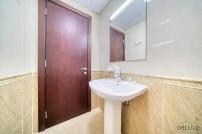 a bathroom with a sink and a wooden door at Ritzy 1BR at Global Golf Residence 2 Sports City by Deluxe Holiday Homes in Dubai