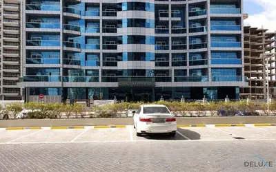 a white car parked in a parking lot in front of a building at Ritzy 1BR at Global Golf Residence 2 Sports City by Deluxe Holiday Homes in Dubai