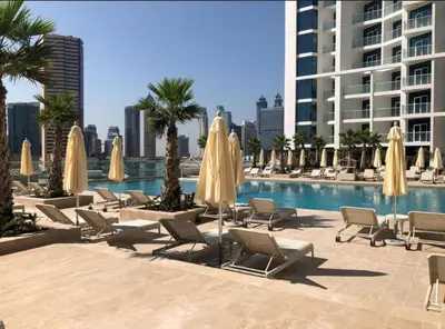 a pool with chairs and umbrellas next to a building at Phineek Homes Luxury Studio With Canal View Damac Maison Prive Business Bay in Dubai