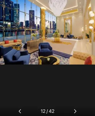 a large lobby with blue chairs and a view of the city at Phineek Homes Luxury Studio With Canal View Damac Maison Prive Business Bay in Dubai