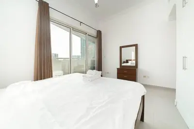 a white bedroom with a large bed and a mirror at StoneTree - Fully Furnished 1BR near Metro Station in Dubai