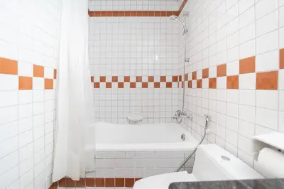 a white tiled bathroom with a tub and a toilet at StoneTree - Fully Furnished 1BR near Metro Station in Dubai