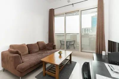 a living room with a brown couch and a table at StoneTree - Fully Furnished 1BR near Metro Station in Dubai