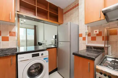 a kitchen with a refrigerator and a washing machine at StoneTree - Fully Furnished 1BR near Metro Station in Dubai