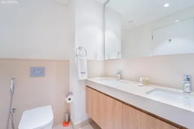 a bathroom with two sinks and a toilet and a mirror at Downtown Views II Tower 1 brand new units in Dubai