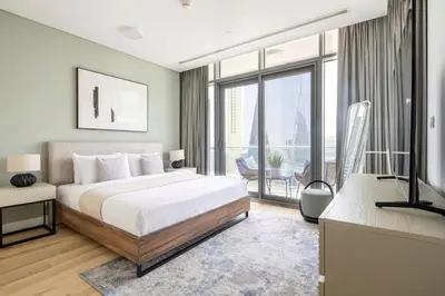 a bedroom with a bed and a television and a balcony at Frank Porter - Burj Daman in Dubai