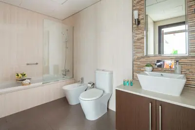 a bathroom with a toilet and a tub and a sink at Frank Porter - Burj Daman in Dubai