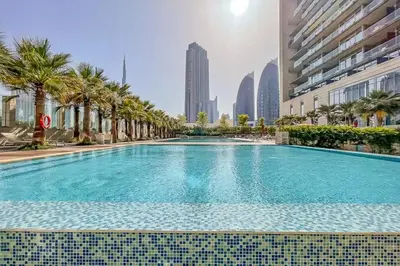 a large swimming pool with palm trees and buildings at Frank Porter - Burj Daman in Dubai