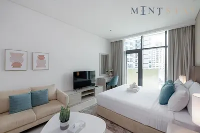 a bedroom with a bed and a couch and a tv at Seven Palm, Palm Jumeirah - Mint Stay in Dubai
