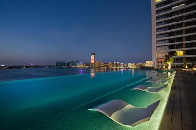 a swimming pool with a view of a city at night at Your beachfront luxe escape experience - Suiteable in Dubai