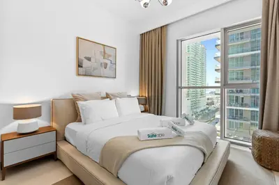 a bedroom with a large bed and a large window at Your beachfront luxe escape experience - Suiteable in Dubai