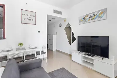 a living room with a large television and a table at StoneTree - Elegant Studio in Peaceful Community in Dubai