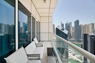a balcony with white chairs and a view of a city at Modern Style 1 BR near Marina Mall and Metro in Dubai