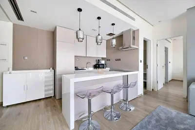 a kitchen with white cabinets and bar stools at Modern Style 1 BR near Marina Mall and Metro in Dubai