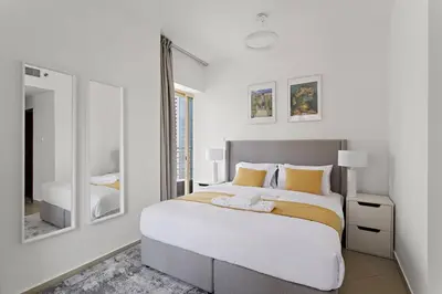 a white bedroom with a large bed and a mirror at StoneTree - Unique 1BR Apartment in JLT in Dubai