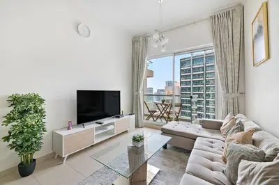 a living room with a couch and a tv at StoneTree - Furnished 1BR with Canal View in Dubai