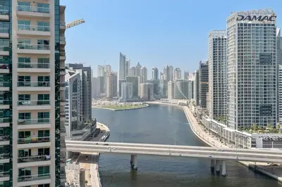 a river in the middle of a city with tall buildings at StoneTree - Furnished 1BR with Canal View in Dubai