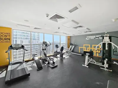 a gym with treadmills and cardio equipment in a building at StoneTree - Furnished 1BR with Canal View in Dubai