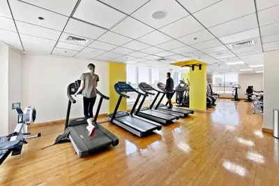a gym with several tread machines and two people in the background at StoneTree - Modern 1 BR Apartment in Dubai Marina in Dubai