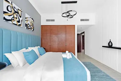 a bedroom with a large bed with blue and white pillows at StoneTree - NEW Furnished 1BR in V3 Tower in Dubai