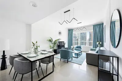 a white living room with a table and chairs at StoneTree - NEW Furnished 1BR in V3 Tower in Dubai