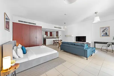 a living room with a large bed and a couch at Sleek Studio in JBR with Pool & Dubai Skyline View in Dubai