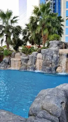 a swimming pool with a waterfall and palm trees at Luxury Paramount Hotel Apt D635 in Dubai