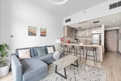 a living room with a blue couch and a kitchen at StoneTree - Stylish 1BR Apartment in MBL Residence in Dubai