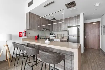 a kitchen with a counter with bar stools and a refrigerator at StoneTree - Stylish 1BR Apartment in MBL Residence in Dubai