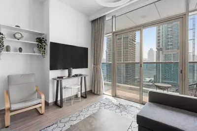 a living room with a tv and a large window at StoneTree - Stylish 1BR Apartment in MBL Residence in Dubai
