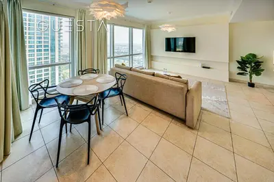 a living room with a couch and a table and chairs at Fairways Tower by Emaar, The Views and Greens in Dubai