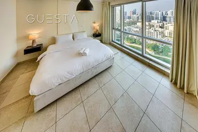 a bedroom with a bed and a large window at Fairways Tower by Emaar, The Views and Greens in Dubai