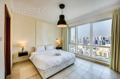 a bedroom with a bed and a large window at Fairways Tower by Emaar, The Views and Greens in Dubai