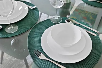 a table with green plates and forks and glasses at StoneTree - NEW Modern 1BR in JLT in Dubai