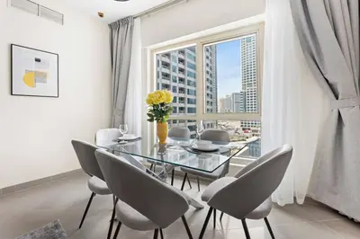 a dining room with a glass table and chairs and a window at StoneTree - Furnished 1BR with Modern Design in Dubai
