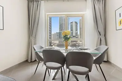 a dining room with a table and chairs and a window at StoneTree - Furnished 1BR with Modern Design in Dubai
