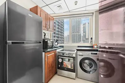 a kitchen with a stainless steel refrigerator and a dishwasher at StoneTree - Furnished 1BR with Modern Design in Dubai
