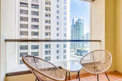 a balcony with two chairs and a table and a large window at GlobalStay 3 Bedroom Apartment near JBR Beach Dubai Marina in Dubai