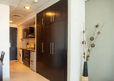 a kitchen with dark wood cabinets and a vase at StoneTree - Family-friendly Studio in Peaceful Community in Dubai