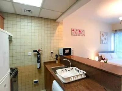 a kitchen with a sink in a room with a bed at StoneTree - Prime Location - Furnished Studio - Near Metro in Dubai
