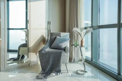 a living room with a chair and a window at Manzil - Stunning 3BR Apt in Paramount nr Burj in Dubai