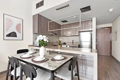 a dining room with a table and chairs and a kitchen at StoneTree - Modern 1BR with Amazing Building Facilities in Dubai