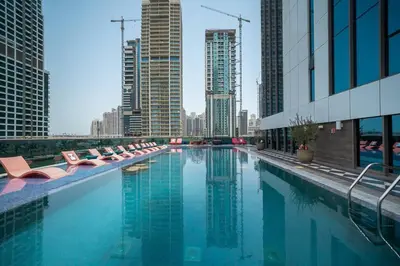 a swimming pool with lounge chairs and a city skyline at StoneTree - Modern 1BR with Amazing Building Facilities in Dubai