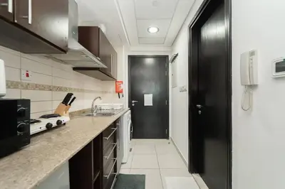 a kitchen with a black door and a kitchen counter at StoneTree - Fully Furnished Studio with Spacious Balcony in Dubai