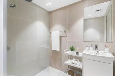 a white bathroom with a shower and a sink at Exclusive Studio by Burj Khalifa and Dubai Mall, High Floor in Dubai